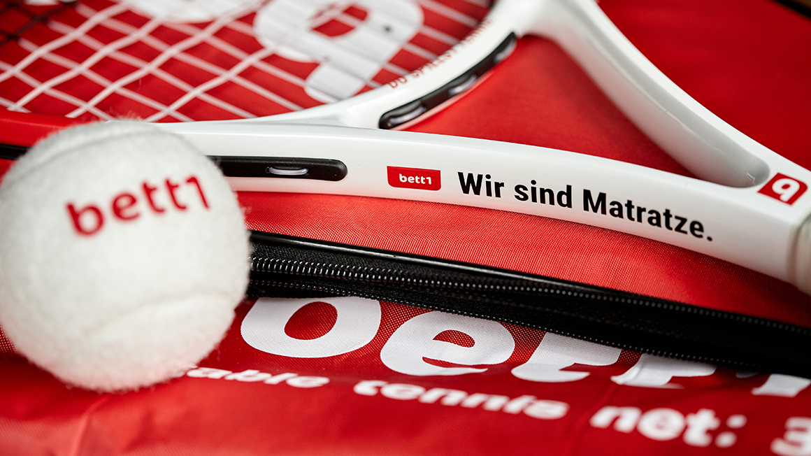 Foto von einem Tennisschläger und Tennisball mit bett1-Aufdruck.