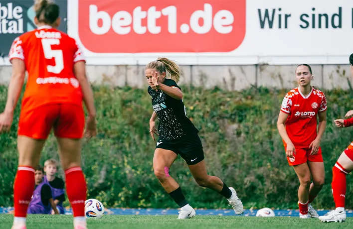 Foto: Eine Person mit Footballhelm und Football in den Händen von hinten.