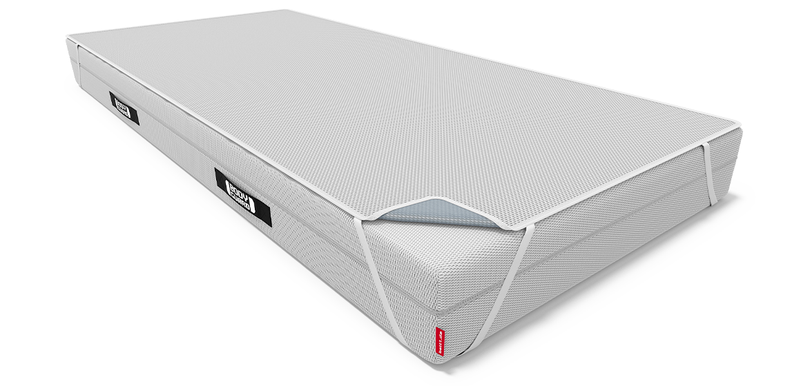 Die BODYGUARD Matratze 200x200 cm bezogen mit der BODYGUARD Inkontinenzauflage 200x200 cm. Eine Ecke der Auflage ist umgeklappt und gibt den Blick auf die wasserdichte Beschichtung frei.