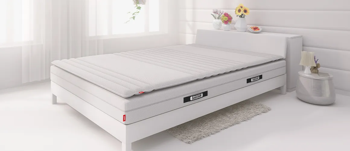 In einem Bett liegt die BODYGUARD® Matratze und darauf der BODYGUARD® Topper.