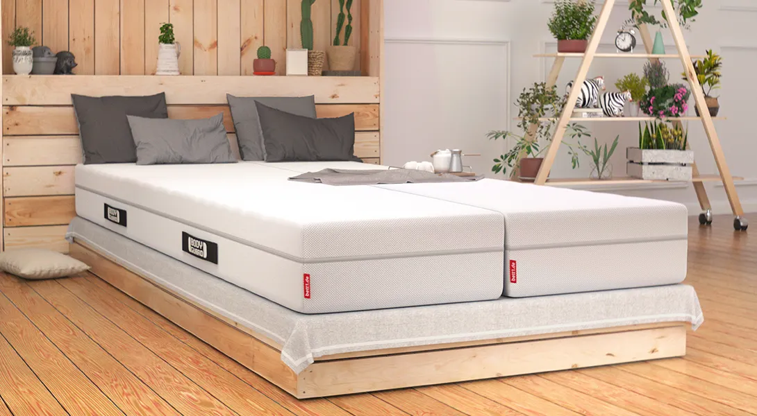 Ein mit hellem Holz ausgestattetes Schlafzimmer. Darin ein Doppelbett mit zwei BODYGUARD Boxspring Matratzen 90x220 cm