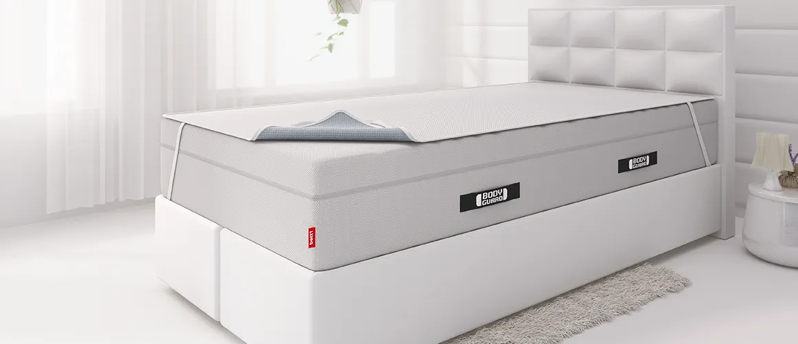 Ein Boxspringbett auf dessen hoher Matratze eine Inkontinenzlauge gespannt ist.