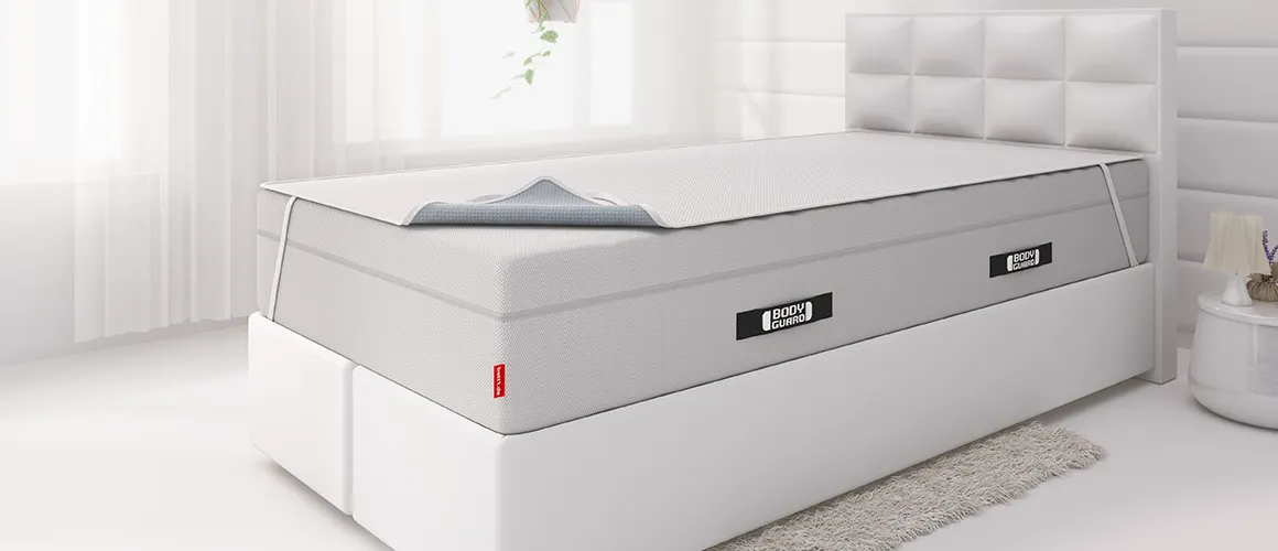 Ein Boxspringbett auf dessen hoher Matratze eine Inkontinenzlauge gespannt ist.