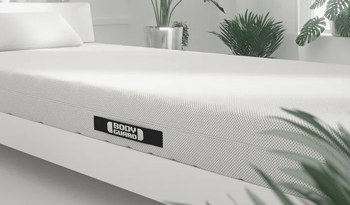 Die BODYGUARD Matratze liegt in einem Bett, das in einem hellen Schlafzimmer steht.