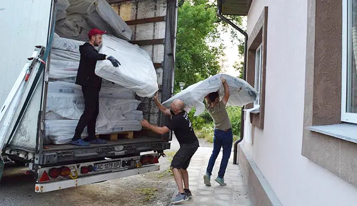 Ein Lkw beladen mit BODYGUARD Matratzen. Eine Person steht auf der Ladefläche und reicht einer zweiten Person eine Matratze. Eine dritte Person trägt eine Matratze weg.