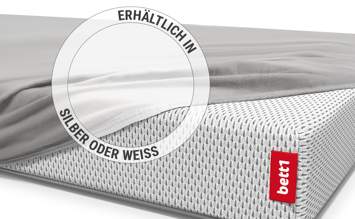Die BODYGUARD® Kindermatratze ist bis auf eine Ecke mit dem Kinder-Spannbettlaken in Silber bezogen. Zoom auf das Laken in der weißen Farbvariante.  Text: Erhältlich in Silber oder Weiß	