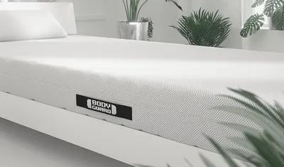 Die BODYGUARD Matratze liegt in einem Bett, das in einem hellen Schlafzimmer steht.