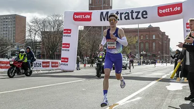 A person runs through a bett1.de archway on the route of the Berlin Generali Half Marathon at the Rote Rathaus of Berlin.
