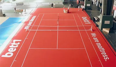 Foto aus der Vogelperspektive: Ein rotes Tennisfeld in einem alten Flugzeughangar.